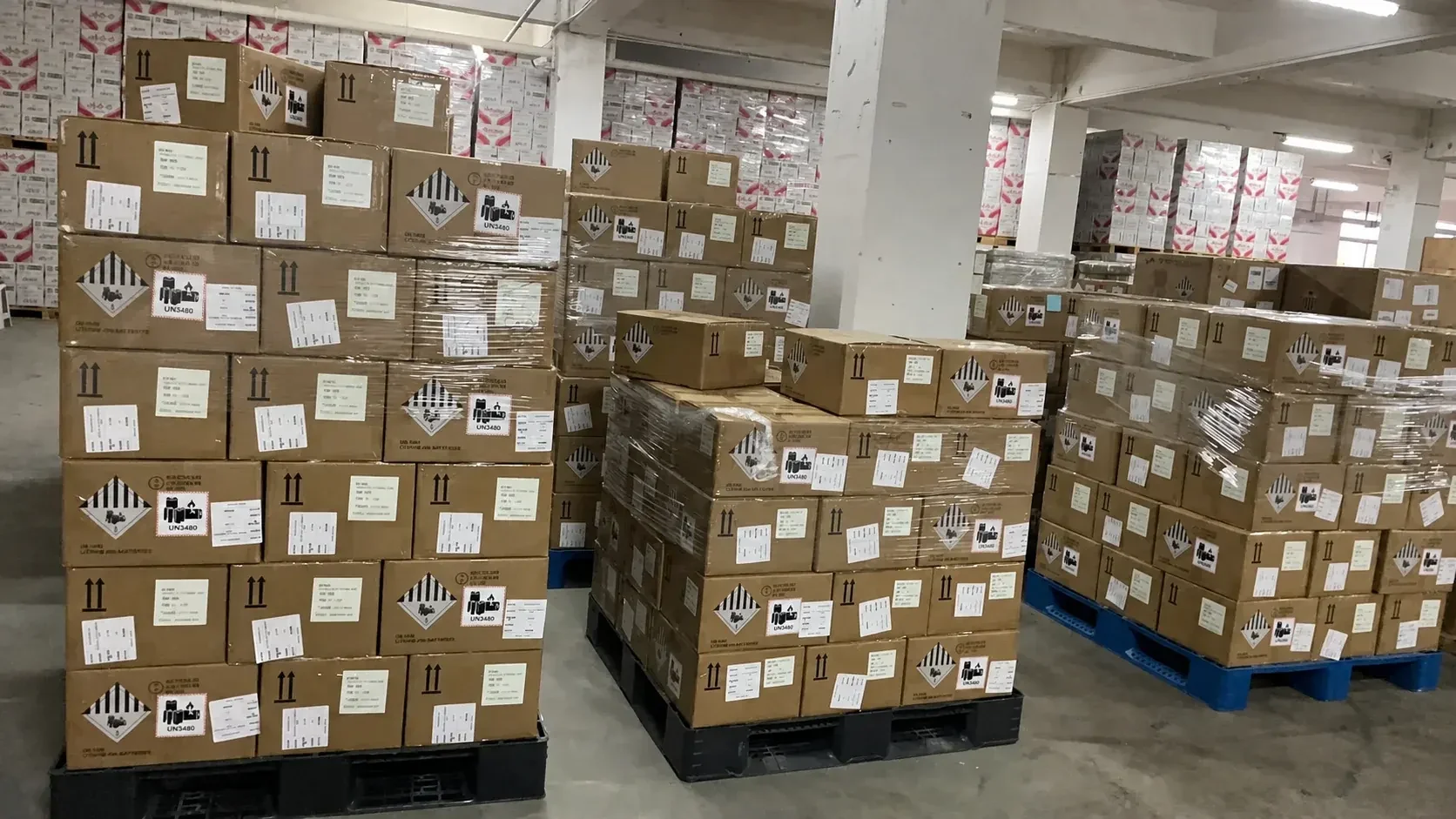 Library photograph of marked battery cartons on warehouse pallets.